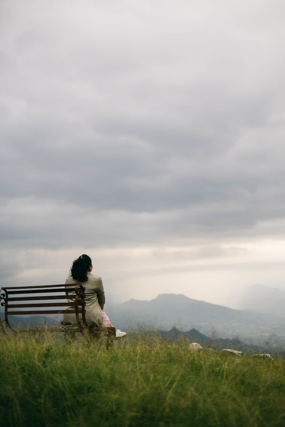 Mujer sentada sola en un banco mirando las montañas
